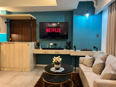 a living room with a couch and a tv at Comfty, Chic & Spacious Room with Parking & WiFi in Manila