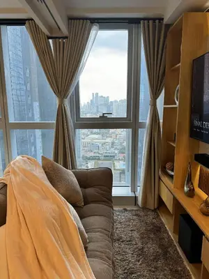 a living room with a couch and a large window at Staycations Up Above 14 @ BGC 1BR in Manila