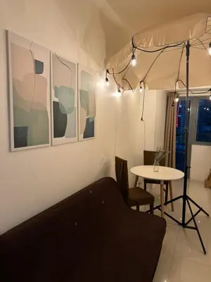 a living room with a bed and a table at Fame Residences Mandaluyong 1 Bedroom City View in Manila