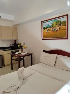 a bedroom with a bed and a kitchen with a table at Dian SUITES 1 in Manila