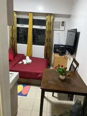 a living room with a red bed and a table at pierrecondotel in Manila