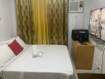 a bedroom with a bed and a television and curtains at pierrecondotel in Manila