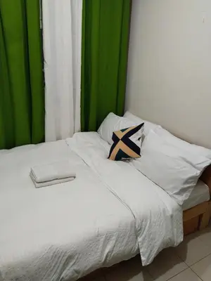 a bed with white sheets and a green curtain at Nicecondotel in Manila
