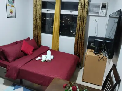 a living room with a red bed and a window at Nicecondotel in Manila