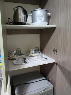 a kitchen shelf with dishes and a pot on it at Nicecondotel in Manila