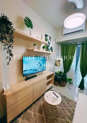 a living room with a flat screen tv on a wooden entertainment center at Emma Mattress 1BR CONDO @ FAME (pool & city view) in Manila