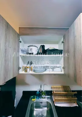 a kitchen with a sink and a shelf with dishes at Emma Mattress 1BR CONDO @ FAME (pool & city view) in Manila
