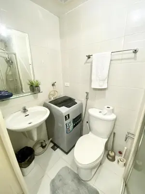 a white bathroom with a toilet and a sink at Cozy Studio with SM Jazz Mall 