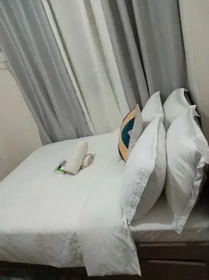 a bed with white sheets and pillows at pierrecondotel in Manila