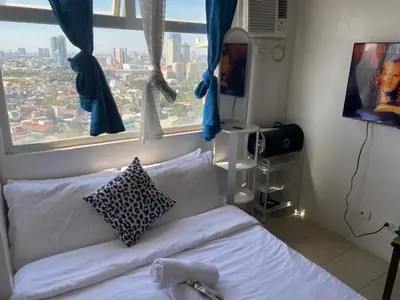 a bedroom with a bed and a large window at pierrecondotel in Manila
