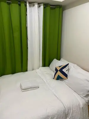 a bed with a green curtain and a pillow on it at pierrecondotel in Manila