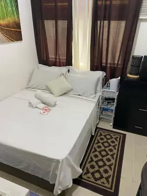 a bedroom with a bed with white sheets and a window at pierrecondotel in Manila