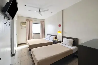 a hotel room with two beds and a flat screen tv at Governor Forbes Inn - Manila City Center in Manila