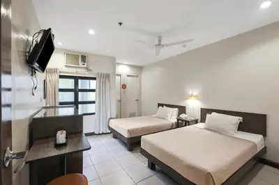 a hotel room with two beds and a television at Governor Forbes Inn - Manila City Center in Manila
