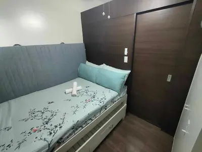 a small bed with a wooden headboard with a white candle on it at 1 Bedroom with Balcony at Air Residences, Makati in Manila