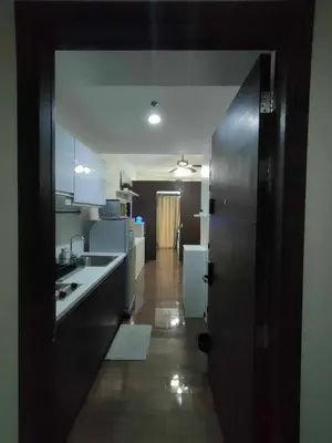 a kitchen with a door open to a kitchen with white appliances at 1 Bedroom with Balcony at Air Residences, Makati in Manila