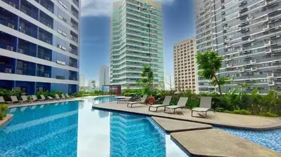 a swimming pool with lounge chairs and some buildings at 1 Bedroom with Balcony at Air Residences, Makati in Manila