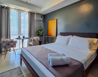 a bedroom with a large bed and a table with chairs at ELUDE Designer Suite Pasig - Prime Location in Manila