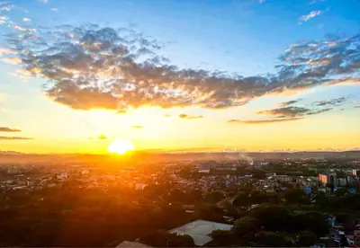 a sunset with the sun setting over a city at ELUDE Designer Suite Pasig - Prime Location in Manila