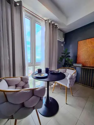 a living room with a table and chairs and a window at ELUDE Designer Suite Pasig - Prime Location in Manila