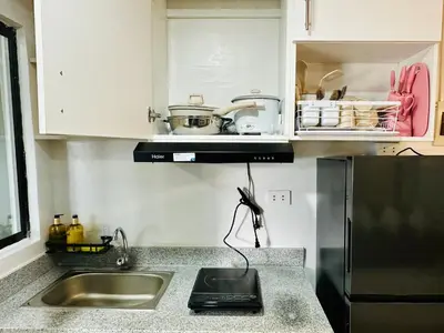 a kitchen with a sink and a refrigerator at Raven's Nest Cozy Condo with Netflix Wi-fi in Imus in Imus
