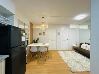a kitchen and living room with a table and a couch at Raven's Nest Cozy Condo with Netflix Wi-fi in Imus in Imus