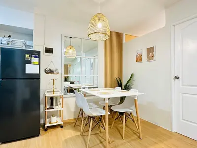 a kitchen and dining room with a table and a refrigerator at Raven's Nest Cozy Condo with Netflix Wi-fi in Imus in Imus