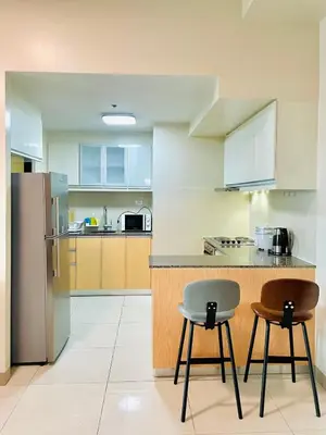 a kitchen with two chairs and a counter and a refrigerator at 1 Queen Bed & 2 double beds at One Uptown Residences with XBOX and Netflix in Manila