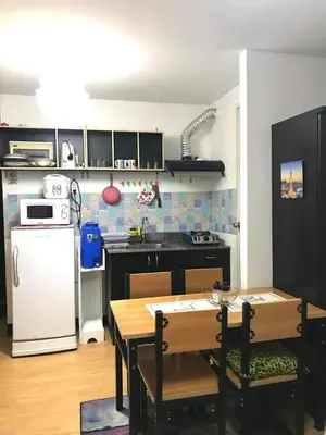 a kitchen with a white refrigerator and a table and chairs at The Escape Pad 7 in Manila