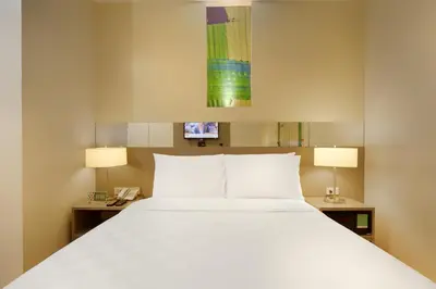 a bedroom with a large white bed with two lamps at Go Hotels Ortigas Center in Manila