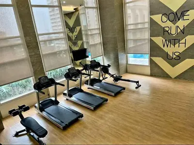 a gym with a row of exercise bikes in a room at High speed internet - Cozy 1BR fully Furnished in Manila