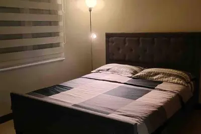 a bedroom with a large bed with a light on it at High speed internet - Cozy 1BR fully Furnished in Manila