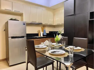 a kitchen with a dining table and a refrigerator at Modern Condo At Venice Residences Bgc #vlrb29k in Manila