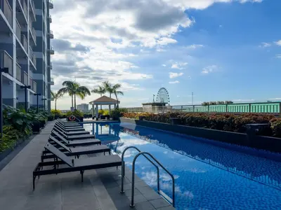 a swimming pool with lounge chairs next to a building at GemstoneBR in SMDC Coast Residences in Manila