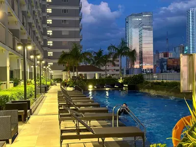 a hotel swimming pool in a city at night at GemstoneBR in SMDC Coast Residences in Manila