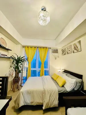 a bedroom with a bed with a chandelier and a window at The 23rd Haven by Kasara Urban Resort Residences in Manila