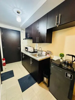 a kitchen with black cabinets and a sink and a dishwasher at The 23rd Haven by Kasara Urban Resort Residences in Manila