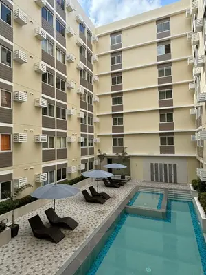 a swimming pool in front of a building with umbrellas at Condo in Silang Fullerton Suites - near tagaytay and nuvali in Silang