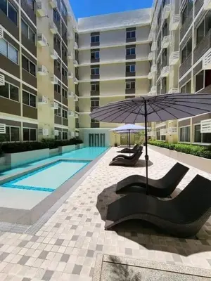 a large building with a pool and an umbrella at Condo in Silang Fullerton Suites - near tagaytay and nuvali in Silang