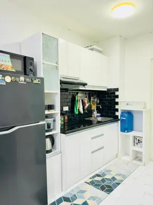 a kitchen with white cabinets and a stainless steel refrigerator at Modern Simplicity: Cozy @Nuvali in Pitland