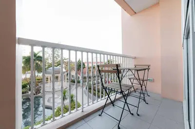 a balcony with chairs and a table and a view of a pool at Studio at Venice Mall, near Airport, BGC & Makati in Manila