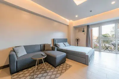 a living room with a couch and a bed at Studio at Venice Mall, near Airport, BGC & Makati in Manila
