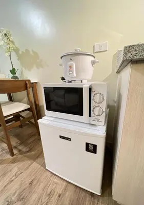 a microwave sitting on top of a white refrigerator at Condo near Nuvali Laguna Technopark St Benedict Church in Bayabasan