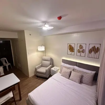 a bedroom with a white bed and a chair at Condo near Nuvali Laguna Technopark St Benedict Church in Bayabasan