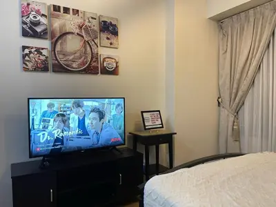 a bedroom with a flat screen tv on a dresser at 8 Adriatico in Manila