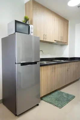 a kitchen with a stainless steel refrigerator and wooden cabinets at Concrete Palms near MOA w/ awesome view of Manila in Manila