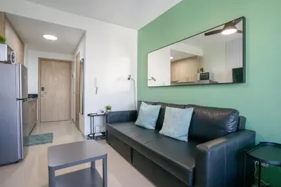 a living room with a black leather couch and a mirror at Concrete Palms near MOA w/ awesome view of Manila in Manila