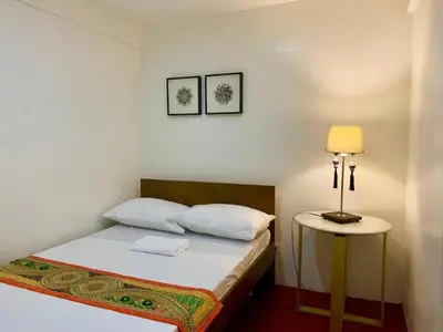 a bedroom with a bed and a lamp on a table at Courtyard Hotel in Manila