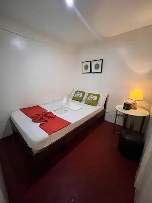 a bedroom with a bed and a table with a lamp at Courtyard Hotel in Manila
