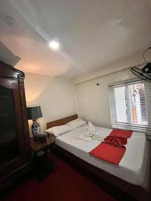 a bedroom with a bed with a red towel on it at Courtyard Hotel in Manila